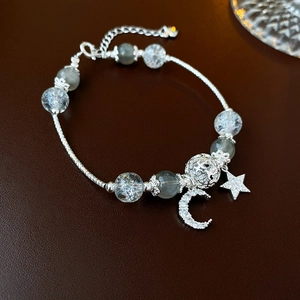 Detail view of silver star and moon charms with crystal beads on a beaded bracelet
