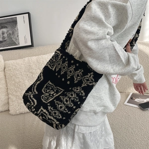 Shoulder bag in plush fabric with black and white paisley pattern worn by a model