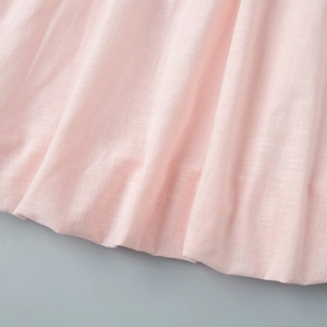 Détail de tissu en lin rose clair montrant des plis froncés et un drapé naturel