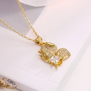 Elegant gold butterfly pendant necklace with zircon stones on a white book background