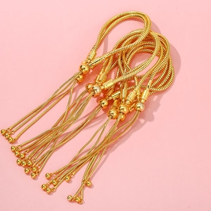 Detailed view of adjustable gold snake chain bracelets with bead charms on pink background