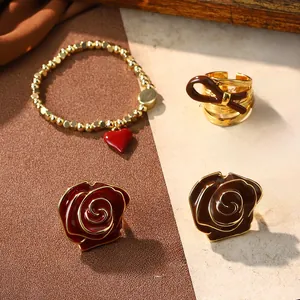 Close-up of retro red enamel rose earrings and brown bow ring on vintage letter paper