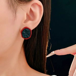 Gros plan de boucles d'oreilles vintage géométriques aux détails texturés rouge et noir