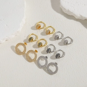 Detail view of gold and silver hoop earrings with zircon beads on white stone blocks