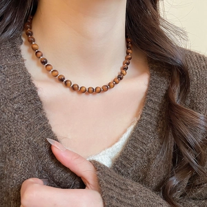 Macro view of brown tiger eye stone beaded necklace with silver spacers on model