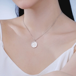 On-model view of silver S925 necklace featuring a modern circular honeycomb textured pendant
