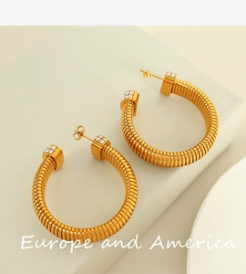 Detailed view of golden screw thread earrings with sparkling white crystals on grey stone
