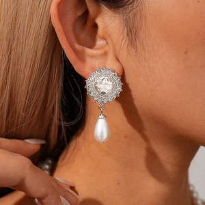 Detail of silver drop earrings with clear crystals and a large white teardrop pearl
