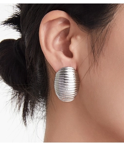 Macro detail of textured silver hoop earrings with horizontal stripes on model