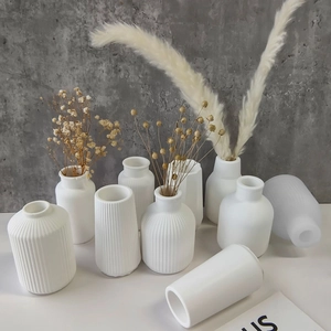 Group of 9 white minimalist ceramic vases in various shapes with dried flower decorations