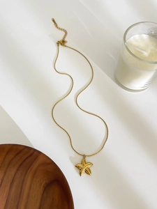 Detailed close-up of golden starfish pendant necklace on a natural white background