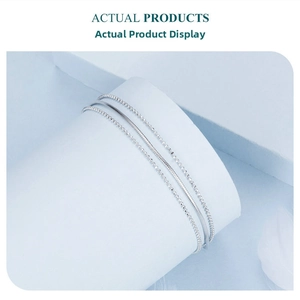 Detailed view of silver multi-layer triple strand chain bracelet on a white display pedestal