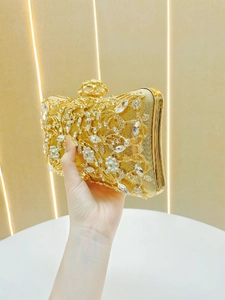 Detail of gold evening bag featuring intricate metal hollow-out and rhinestone floral patterns