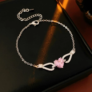 Macro detail of silver bracelet with pink heart-shaped zircon on black leather box