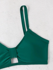 Detailansicht eines dunkelgrünen Bikini-Oberteils mit dünnen Trägern und Cut-out-Knoten