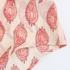Detailed close-up of beige chiffon fabric with red paisley print and gold pinstripes