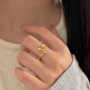 Detailed view of an adjustable gold wave ring with three polished metal spheres