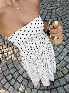 Flat lay of off-the-shoulder polka dot dress with straw bag and golden accessories