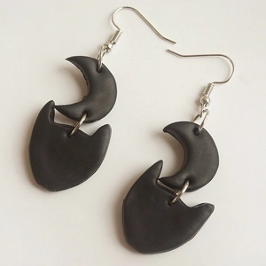 Detail of handmade black clay moon and cat head drop earrings with silver hooks