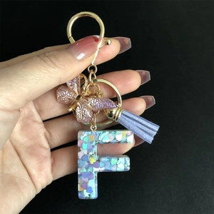 Detail of resin letter F keychain with purple butterfly charm and heart sequins