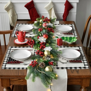 Close-up of Christmas table decor featuring artificial pine wreath with warm LED lights