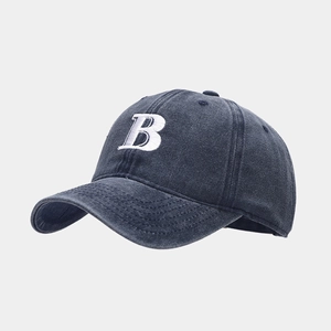 Detail of white embroidered letter B on a washed navy denim baseball cap crown