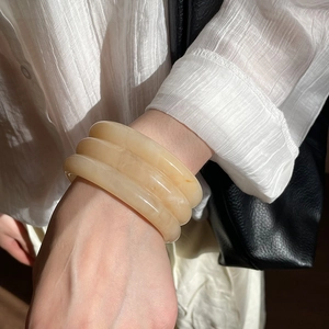 Close-up of three-layer amber resin bangle bracelets with smooth cream finish for women