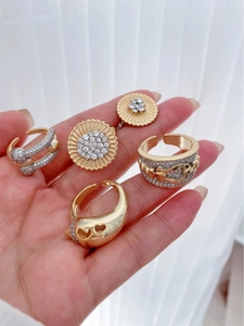 Detailed close-up of 18K gold-plated rings with zircon stones held in hand