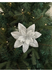Close-up of sparkling silver artificial Christmas flower on a decorated pine tree branch