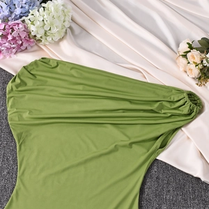 Close-up of grass green off-shoulder dress with ruched elastic fabric and floral accents