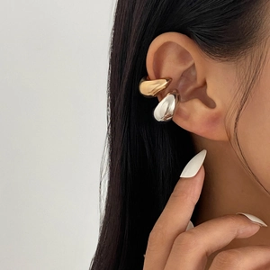 Minimalist gold and silver C-shaped drop ear cuffs shown on model's ear