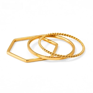 Close-up of three-piece gold stacking rings with geometric, smooth, and twisted bands