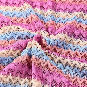 Détail macro du tissu en maille ondulée colorée avec rayures roses et texture ajourée