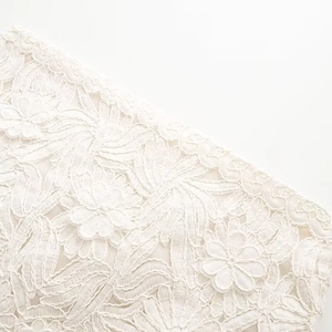 Detailed macro view of white floral lace fabric with exquisite textured embroidery