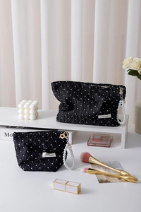 Detail of polka dot cosmetic bag with pearl handles and soft ruffled fabric texture