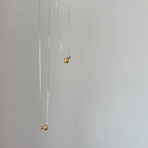 Detailed view of dual-tone gold and silver bead pendants on thin titanium steel chains