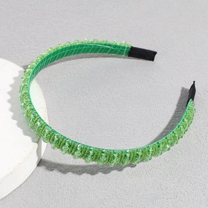 Detail of green handmade beaded headband with crystal rhinestones on a grey stone base
