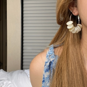 Detail of cream-colored resin discs stacked on gold hoops shown on a model