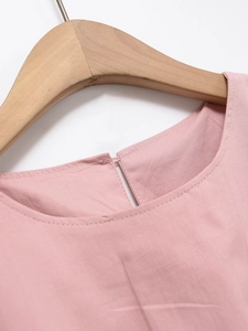 Détail du col rond et de la fermeture boutonnée au dos d'une robe rose en coton
