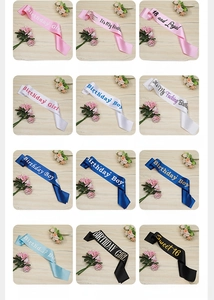 Various satin birthday sashes in pink, blue and black displayed on wood background