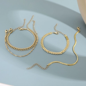 Detail shot of multi-layered gold metal chains including Cuban and herringbone link styles
