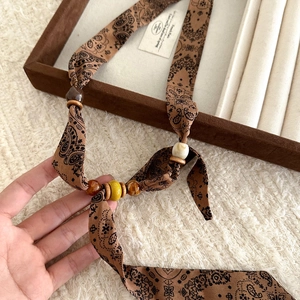 Detailed view of bohemian paisley fabric necklace with brown ceramic and wooden beads