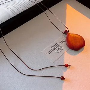 Vintage red-brown wooden flask pendant necklace with adjustable brown cord on beige canvas