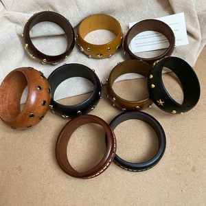 Détail de divers bracelets vintage en bois à rivets déclinés en plusieurs tons terreux