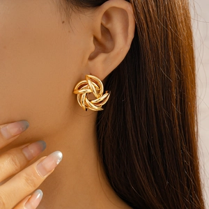 Close-up of golden geometric twisted spiral flower earrings on model with metallic luster