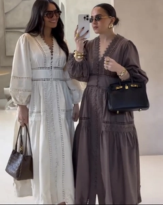 Détail de robe à manches longues, col en V, broderie ajourée et boutons sur le devant