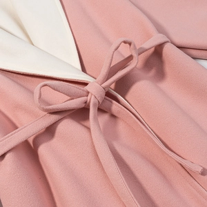Detail view of the pink wool coat featuring a waist tie and white contrast lining