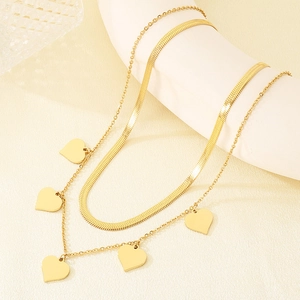 Détail du collier doré double rang avec chaîne serpent et cinq petits cœurs