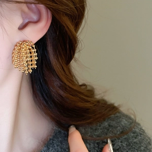 Detailed view of gold tassel earrings with bead chains on model showing elegant drape style