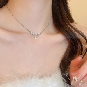 Vue détaillée d'un collier argenté avec pendentif zircon en V sur le cou du modèle